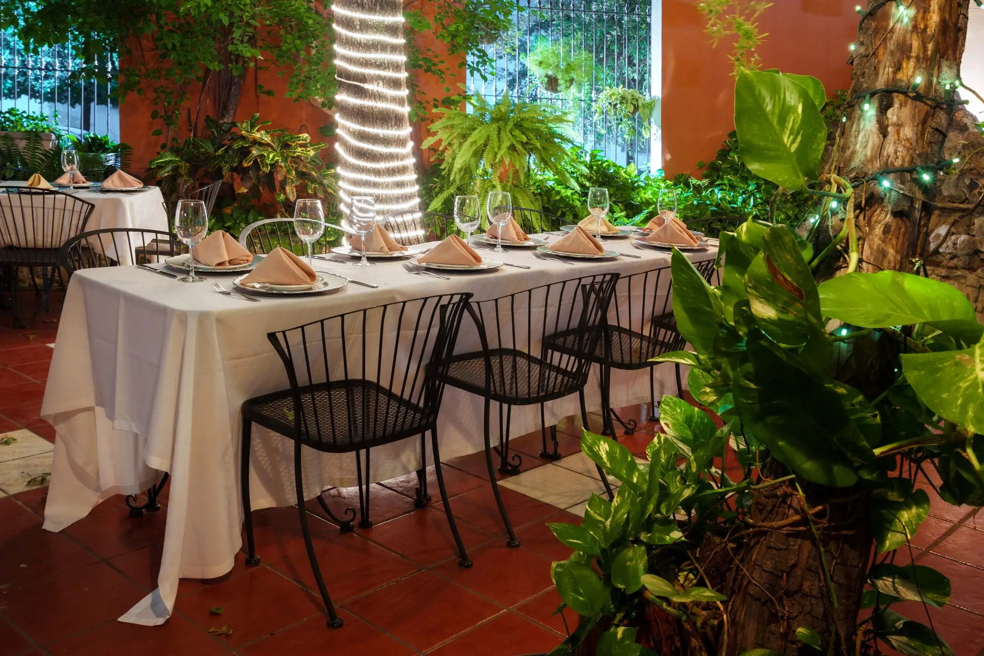 Una mesa vestida de blanco entre las plantas del Jardín, junto al árbol de luces