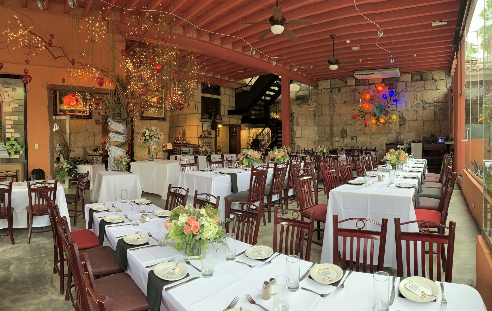 Las mesas del Comedor Principal vestidas de blanco, junto al muro de piedra
