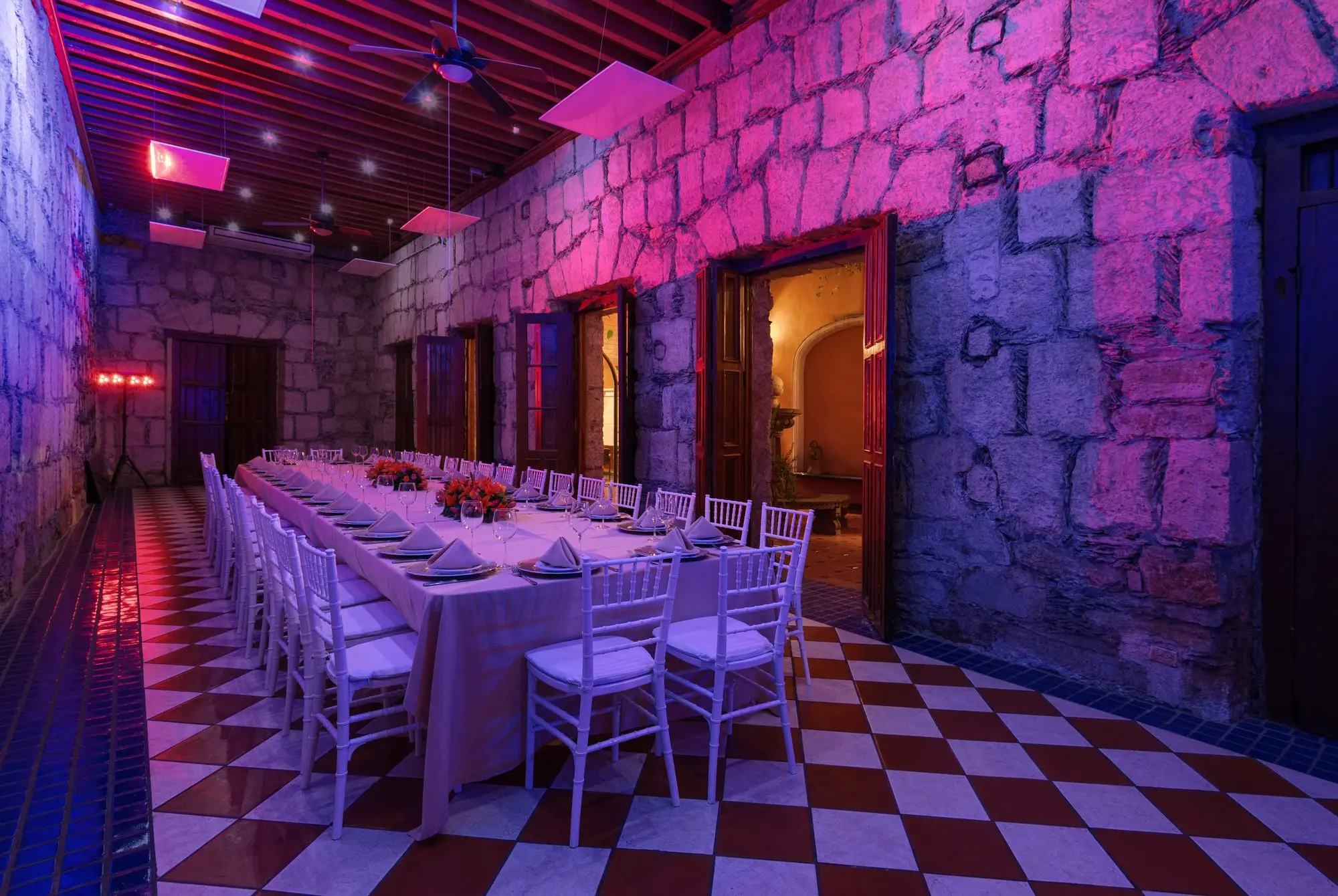 El Romancera con iluminación malva sobre los muros de sillar, montado para una cena larga