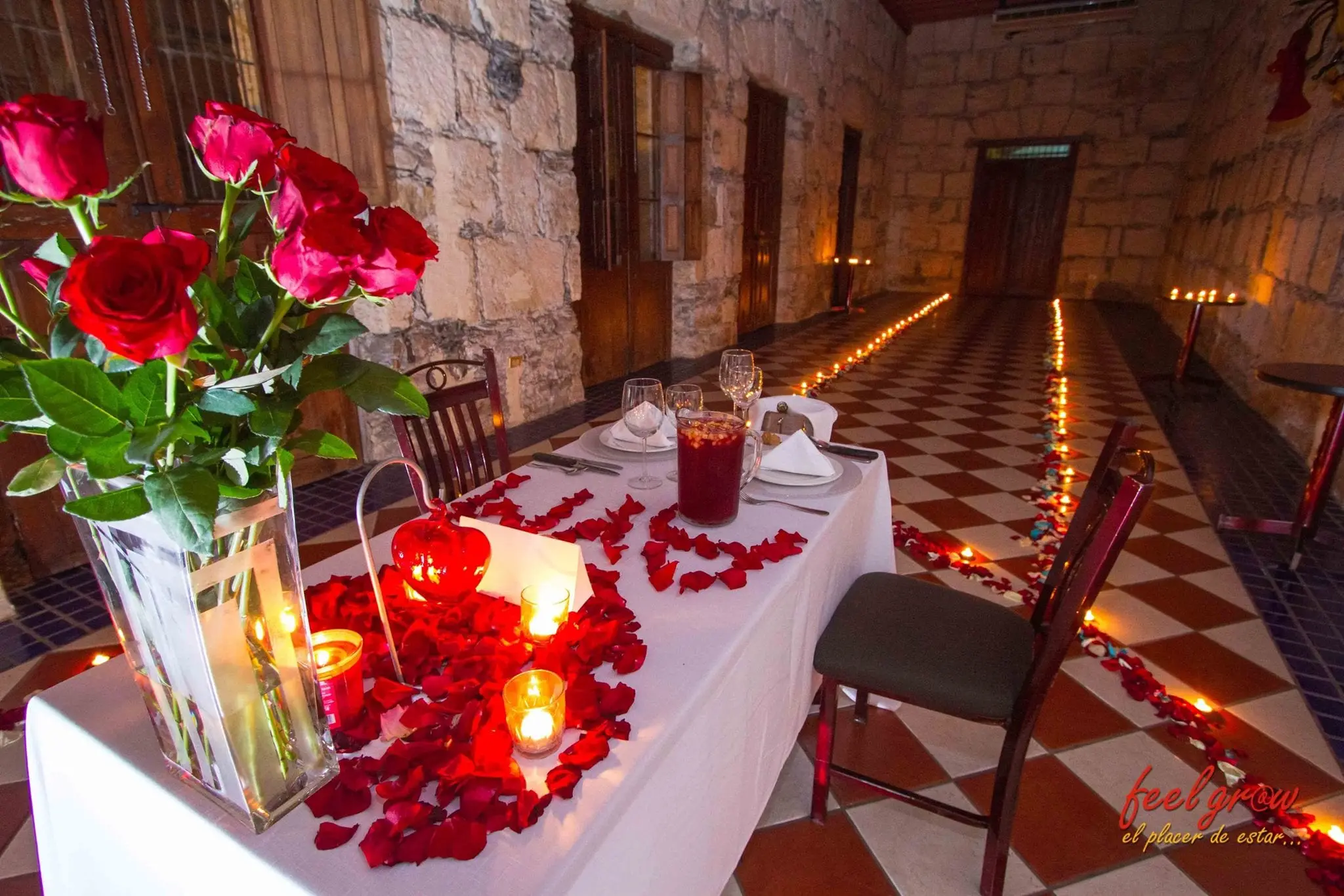 La mesa con rosas y pétalos, y el camino de velas hacia el fondo del salón